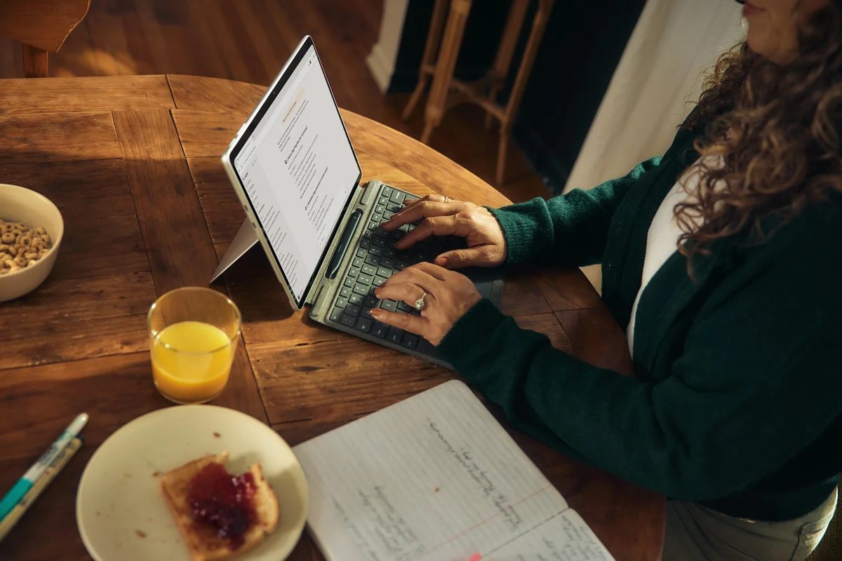 person typing on a laptop at a wooden table