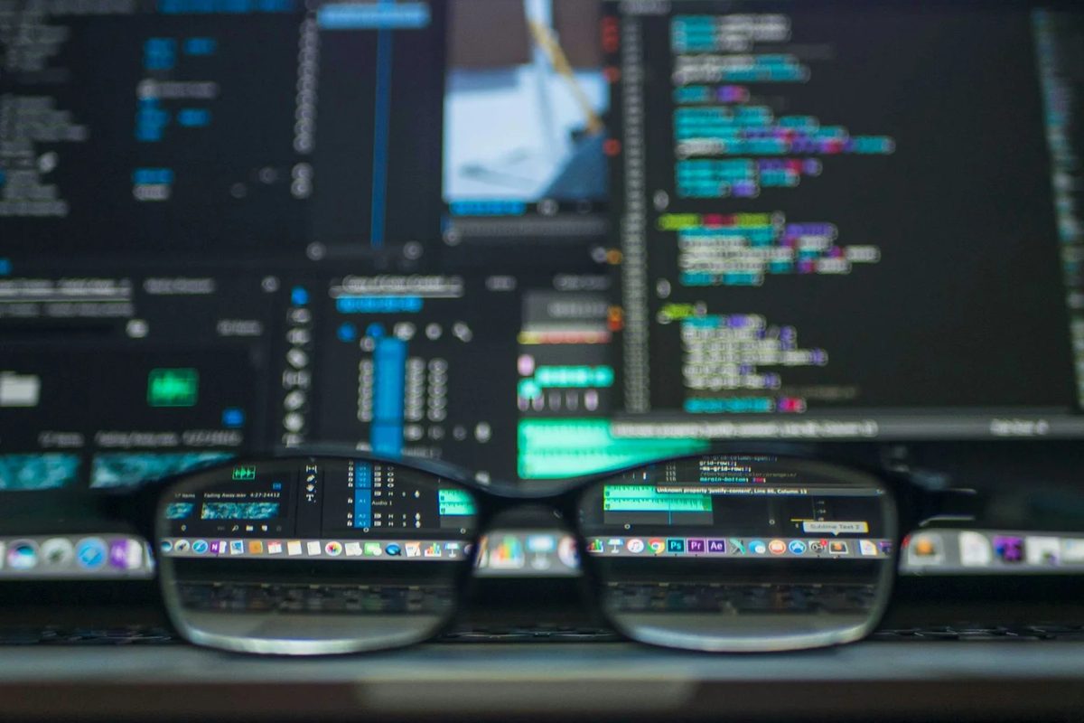 closeup photo of eyeglasses in front of a screen of code